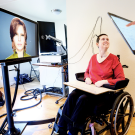 Ann, a research participant in a study of speech neuroprostheses led by UCSF's Edward Chang, is connected to computers that translate her brain signals into the speech and facial movements of an avatar. At left is UCSF clinical research coordinator Max Dougherty. (Photo by Noah Berger)